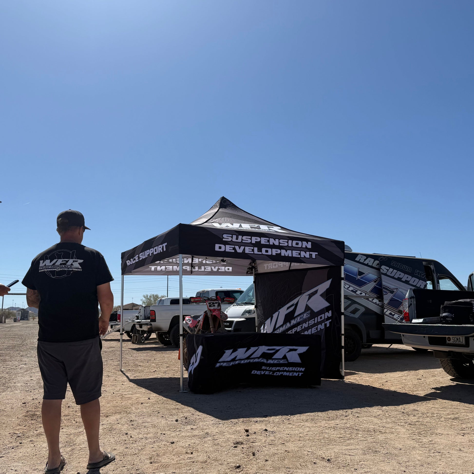Two people standing near a WFR branded tent and vehicles in an outdoor setting.