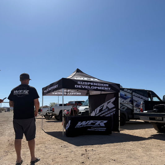 Two people standing near a WFR branded tent and vehicles in an outdoor setting.